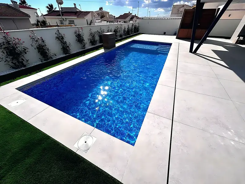 Rectangular pool with deep blue glass mosaic, wide entry steps and light grey porcelain paving, built by ORIGEN, Costa Blanca