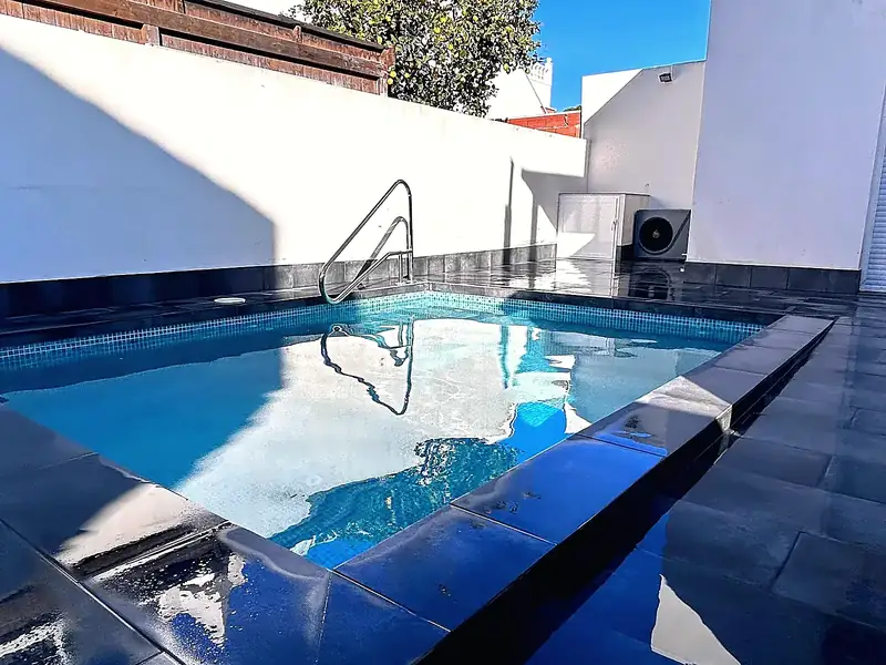Compact plunge pool with light blue mosaic, dark polished porcelain surround, steel handrail and white courtyard walls