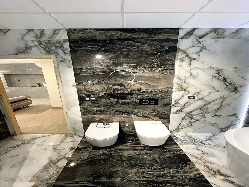 Bathroom renovation in black and white marble-effect porcelain, wall-hung toilet and bidet, freestanding bath and LED mirror